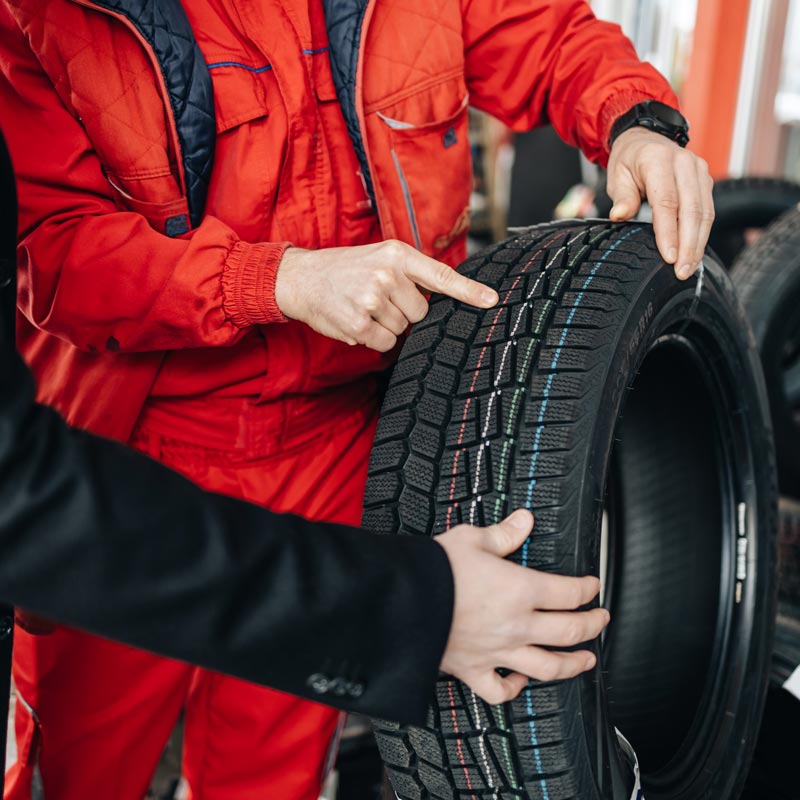 mechanic pointing out tire treads to customer