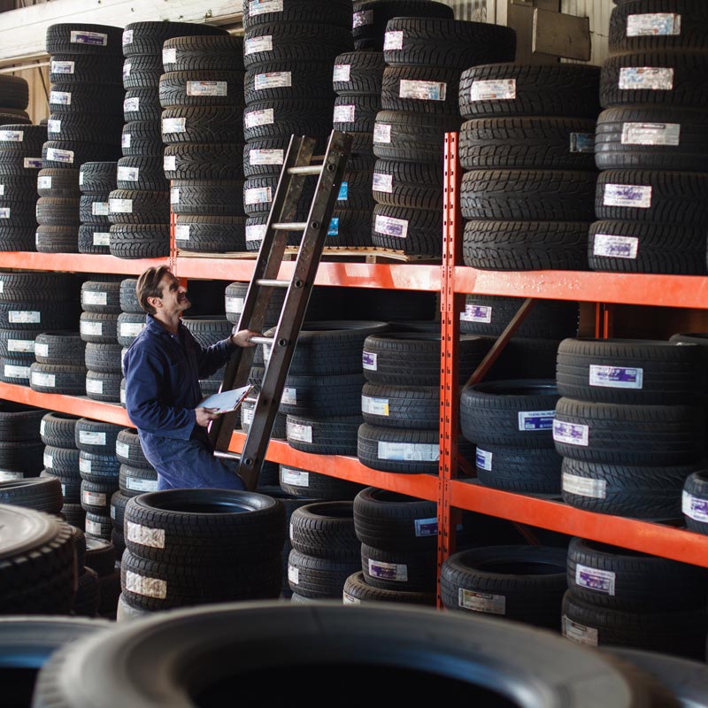 mechanic pulling tires down from shelf