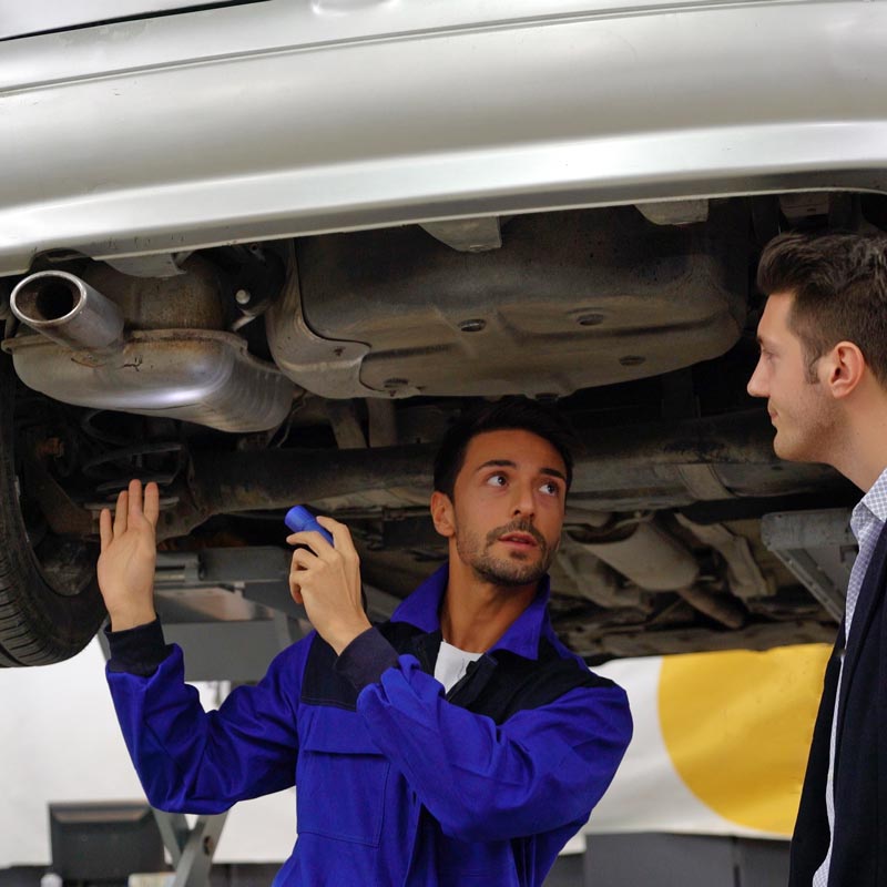 mechanic pointing out issues on car underbody to client